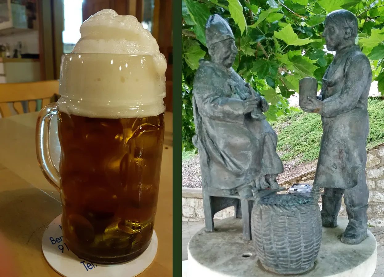 Links eine Maß Kommunbier mit hoher Schaumkrone, rechts Bronzefiguren am Brunnen in Neuhaus